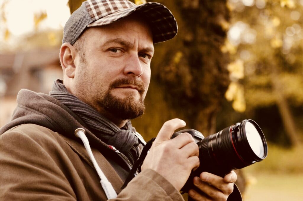 Fotograf André Looft mit Kamera in der Hand. Er fotografiert für Helios Media Werder.