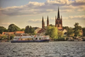 Die Insel Werder (Havel) aus der Wasserperspektive mit Schiff an einem sonnigen Tag. Im Hintergrund ist die Heilig Geist Kirche zu sehen.